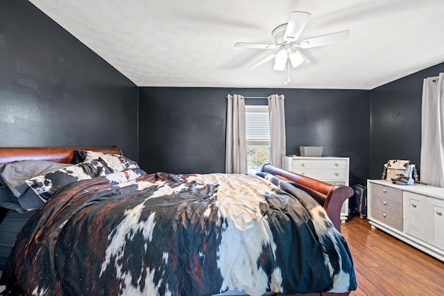 bedroom with a textured ceiling, light wood-type flooring, and ceiling fan