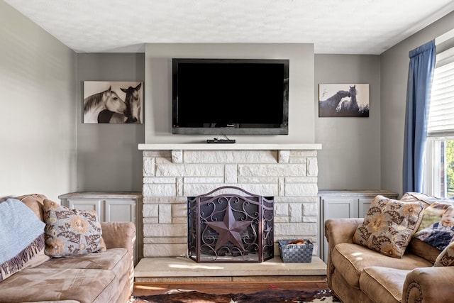 living room with a stone fireplace and a textured ceiling