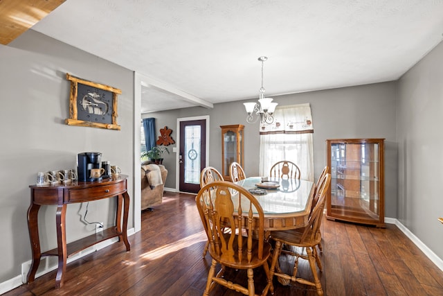 dining area featuring an inviting chandelier, a textured ceiling, and dark wood-type flooring