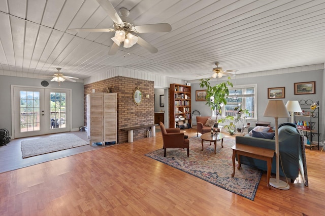 living room featuring french doors, light wood-type flooring, brick wall, and ceiling fan