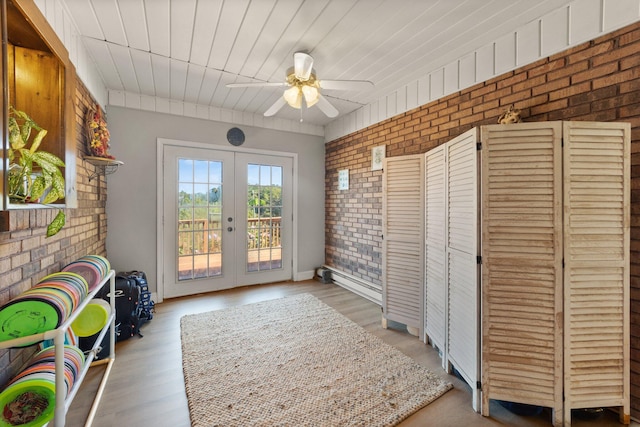 entryway featuring french doors, brick wall, light hardwood / wood-style flooring, and ceiling fan