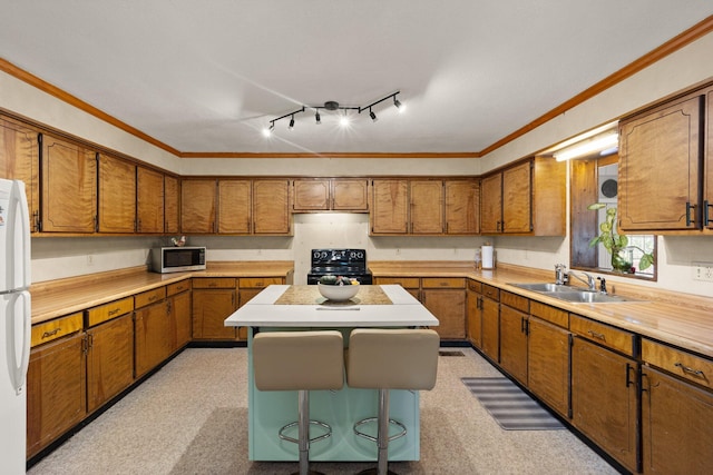 kitchen with a kitchen island, sink, crown molding, white refrigerator, and black range