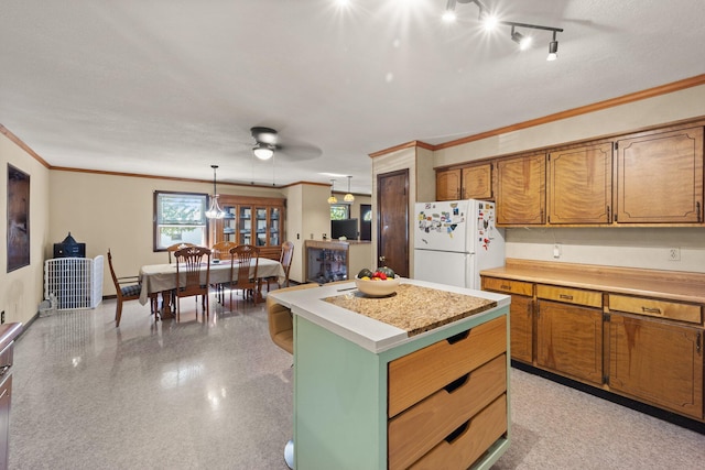 kitchen featuring ceiling fan, pendant lighting, a center island, crown molding, and white fridge