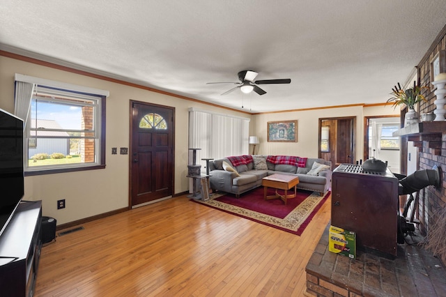 living room with ornamental molding, ceiling fan, wood-type flooring, and a textured ceiling