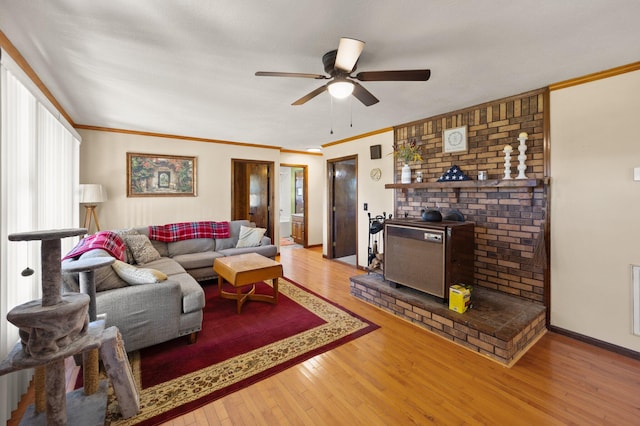 living room with a wood stove, ornamental molding, hardwood / wood-style floors, and ceiling fan