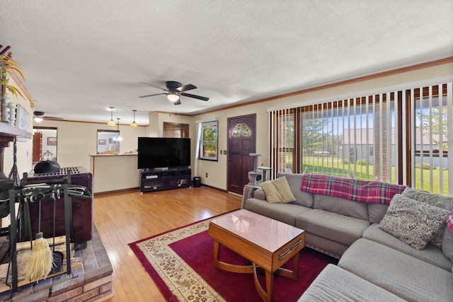 living room featuring ornamental molding, hardwood / wood-style flooring, ceiling fan, and a textured ceiling