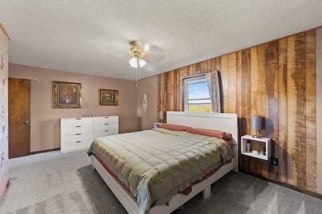 carpeted bedroom featuring ceiling fan, a textured ceiling, and wood walls