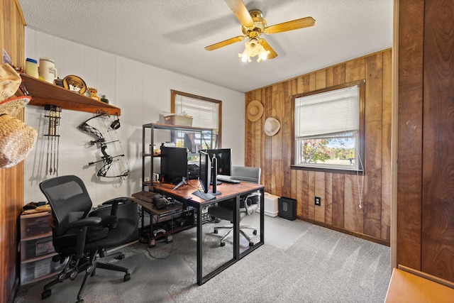 home office featuring wooden walls, ceiling fan, and a textured ceiling