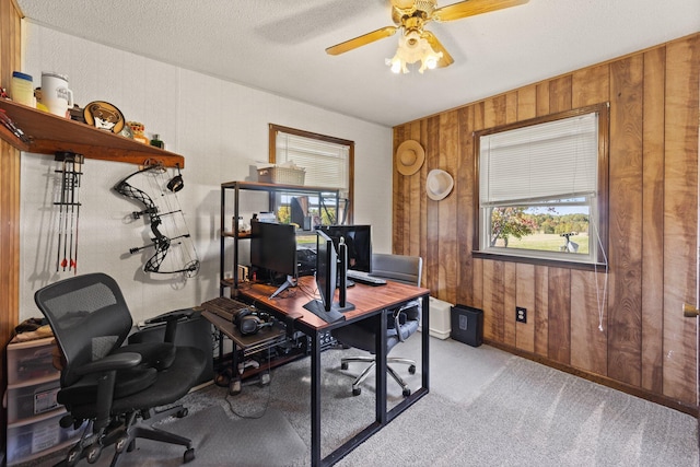 office with light carpet, wooden walls, ceiling fan, and a textured ceiling