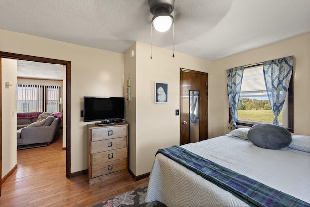 bedroom featuring ceiling fan, wood-type flooring, a textured ceiling, and multiple windows