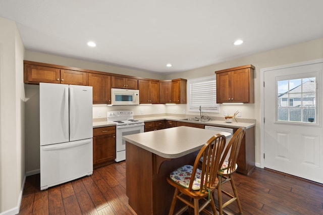 kitchen with white appliances, sink, dark hardwood / wood-style flooring, and a center island