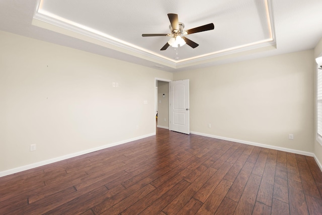 unfurnished room with ceiling fan, a tray ceiling, and dark hardwood / wood-style floors