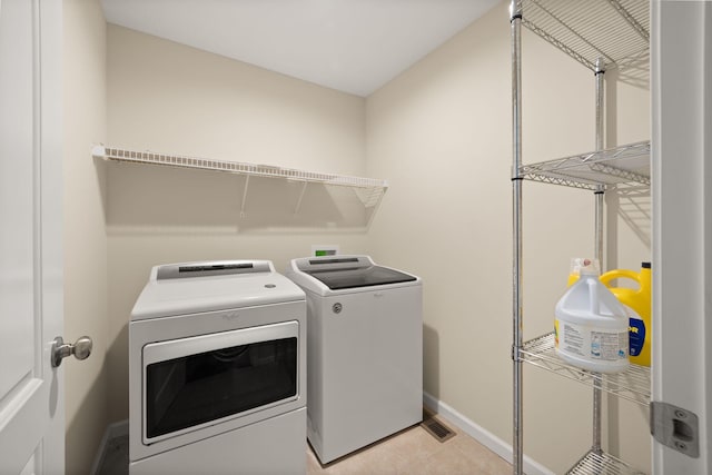 laundry area featuring washing machine and dryer and light tile patterned floors