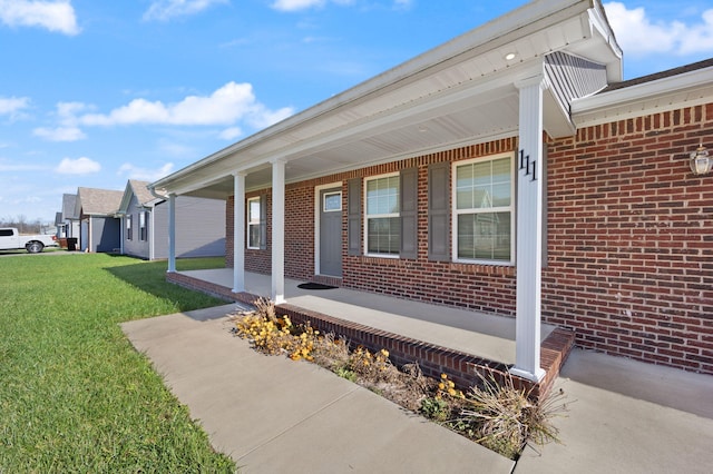 doorway to property with covered porch and a yard