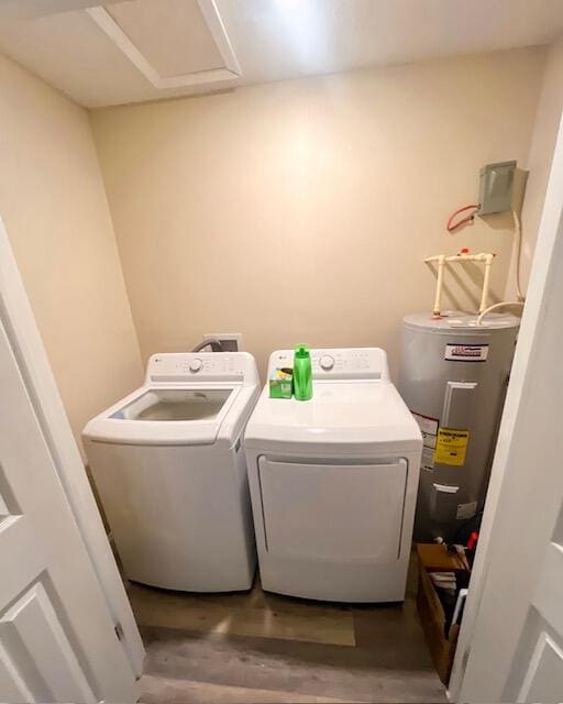 washroom featuring washing machine and clothes dryer, water heater, and hardwood / wood-style flooring