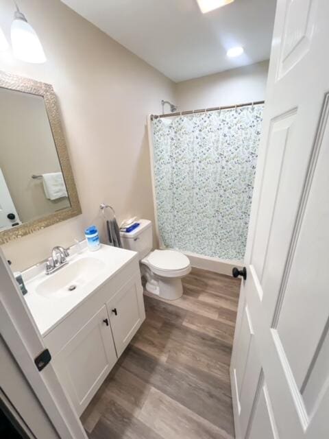 bathroom featuring hardwood / wood-style flooring, toilet, vanity, and a shower with curtain