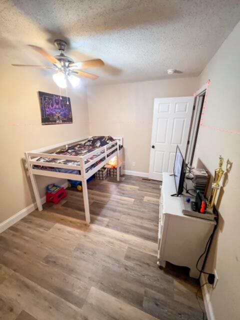 bedroom featuring ceiling fan, a textured ceiling, and wood-type flooring