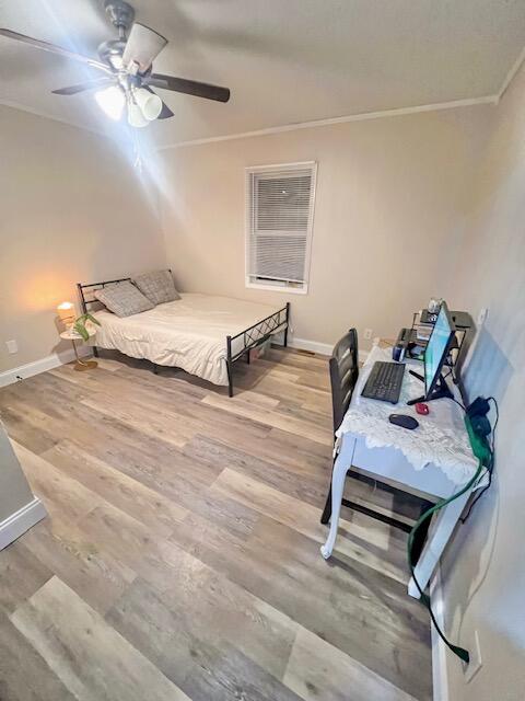 bedroom featuring ornamental molding, ceiling fan, and wood-type flooring