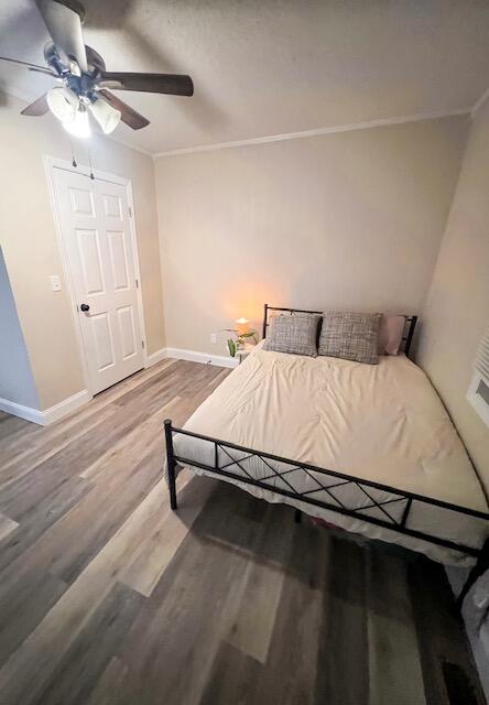 bedroom featuring hardwood / wood-style flooring, crown molding, and ceiling fan