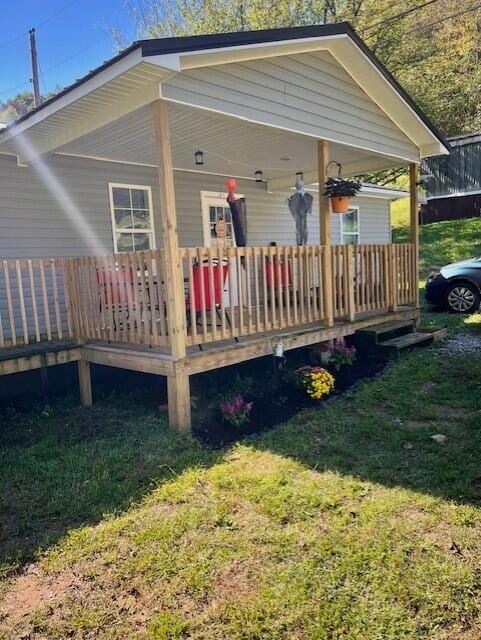 back of property with a lawn and a deck