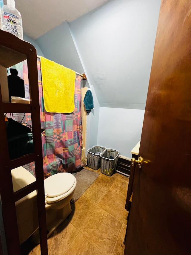 bathroom featuring walk in shower, vaulted ceiling, toilet, and tile patterned flooring