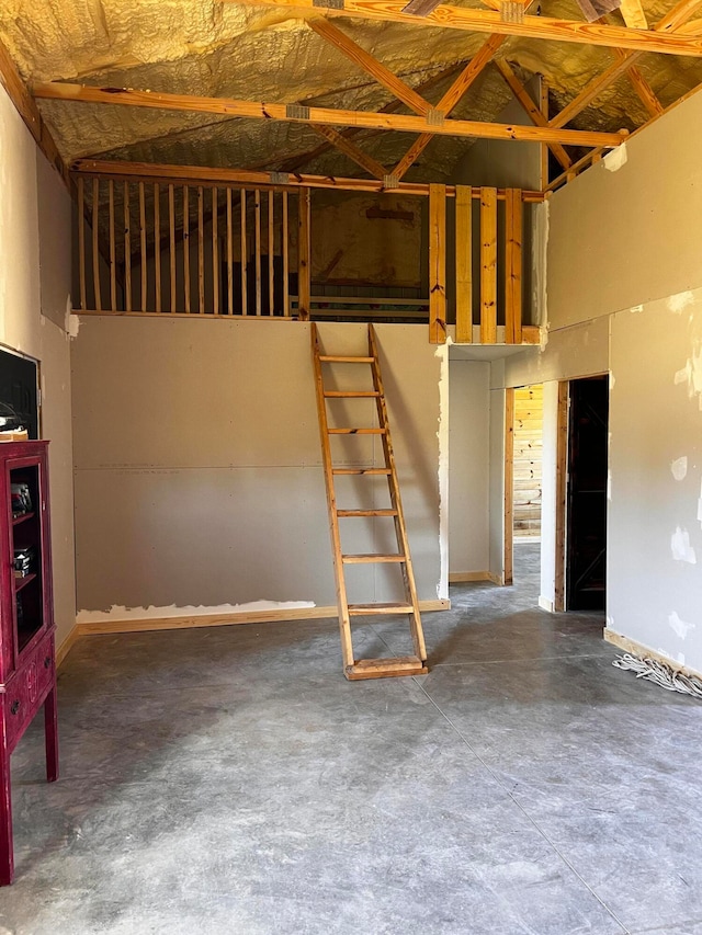 interior space featuring high vaulted ceiling and concrete flooring