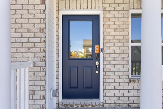 view of exterior entry featuring brick siding