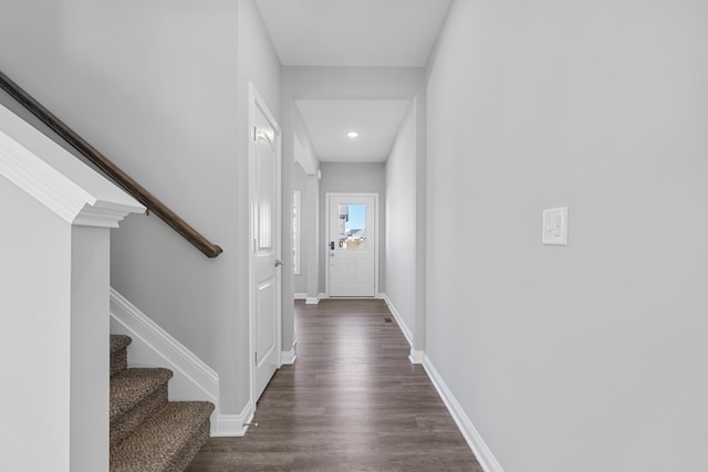 hallway with dark wood finished floors, stairway, and baseboards