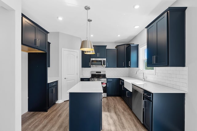 kitchen featuring a center island, sink, stainless steel appliances, decorative light fixtures, and hardwood / wood-style flooring