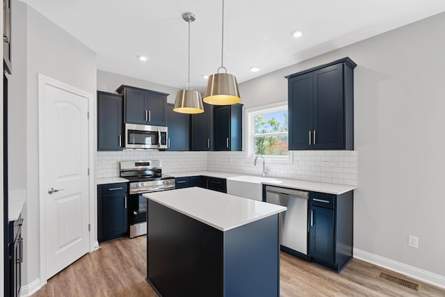 kitchen featuring light wood finished floors, visible vents, decorative backsplash, appliances with stainless steel finishes, and a sink