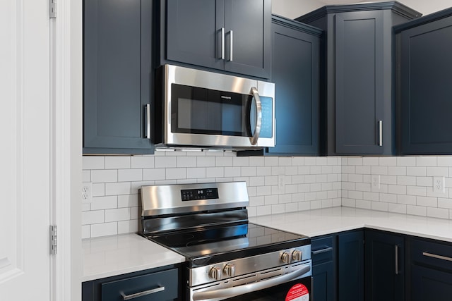 kitchen featuring stainless steel appliances, backsplash, light countertops, and blue cabinets