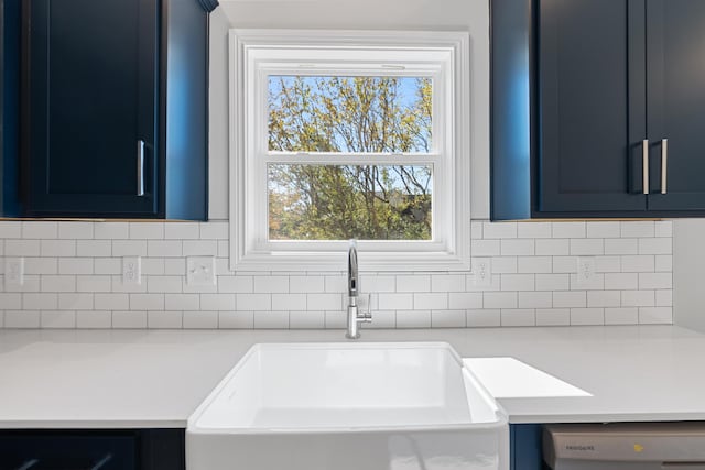 kitchen with dishwashing machine, a sink, light countertops, and blue cabinets