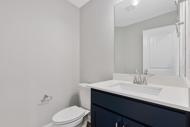 half bathroom with visible vents, vanity, toilet, and baseboards