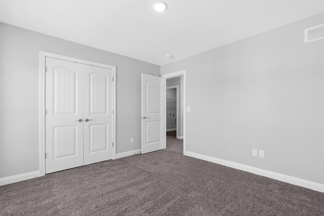 unfurnished bedroom featuring dark carpet and a closet