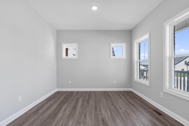 unfurnished room featuring dark wood-style floors, visible vents, and baseboards