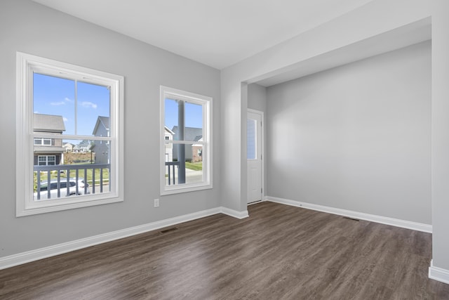 unfurnished room with dark wood-type flooring, visible vents, and baseboards