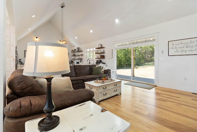 living room with high vaulted ceiling and light hardwood / wood-style flooring