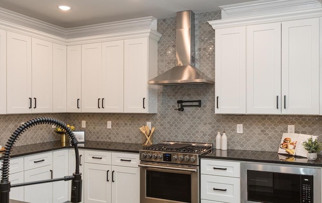 kitchen featuring decorative backsplash, white cabinets, stainless steel stove, wall chimney range hood, and a sink