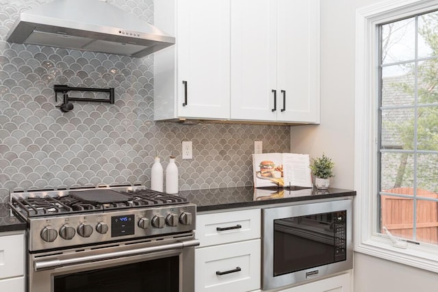 kitchen with white cabinets, dark countertops, built in microwave, extractor fan, and stainless steel range with gas stovetop