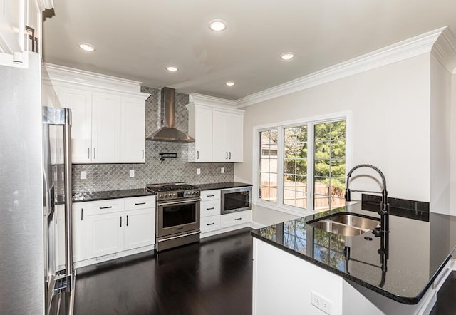 kitchen with a sink, appliances with stainless steel finishes, wall chimney range hood, dark wood finished floors, and crown molding