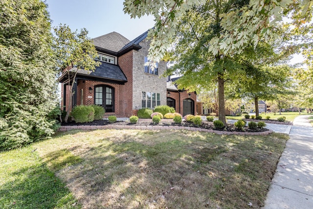 view of front of home featuring brick siding, a front lawn, and a shingled roof