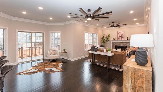 office space with baseboards, wood finished floors, crown molding, a stone fireplace, and recessed lighting