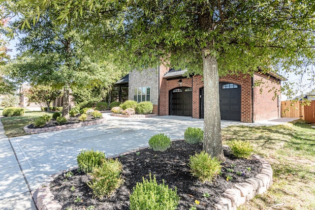 view of front of home with a garage, driveway, fence, and brick siding