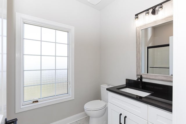 bathroom with toilet, vanity, a wealth of natural light, and baseboards