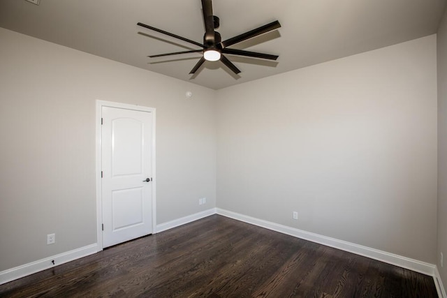 spare room featuring dark wood-style flooring, ceiling fan, and baseboards