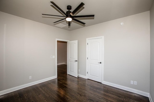 unfurnished room with visible vents, dark wood finished floors, baseboards, and ceiling fan