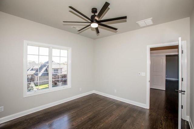 empty room featuring ceiling fan, dark wood-style flooring, visible vents, and baseboards