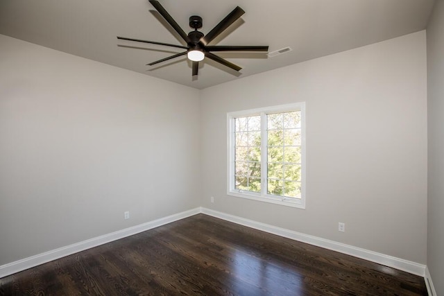 spare room with dark wood-style floors, visible vents, ceiling fan, and baseboards