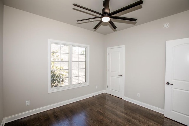 empty room featuring dark wood finished floors, a ceiling fan, and baseboards