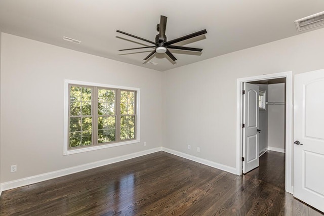 spare room featuring dark wood-style floors, visible vents, baseboards, and a ceiling fan